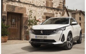 Frontal del nuevo Peugeot 3008 PHEV frente a una casa vieja. Puedes probarlo en Tumasa Huesca y Monzón