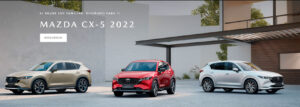 Gama de vehículos Mazda CX5 de diferentes colores. Hay uno a la izquieda dorado, otro en el centro rojo y otro blanco nacarado a la derecha.