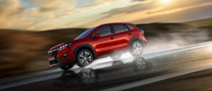 Foto del Suzuki S-Cross, todoterreno en color rojo levantando agua al pasar con las ruedas a toda velocidad